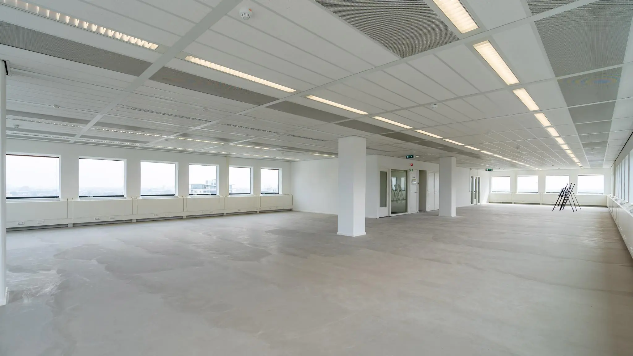 Licht en ruim leeg kantoorpand aan het Johanna Westerdijkplein met grote ramen en systeemplafond.